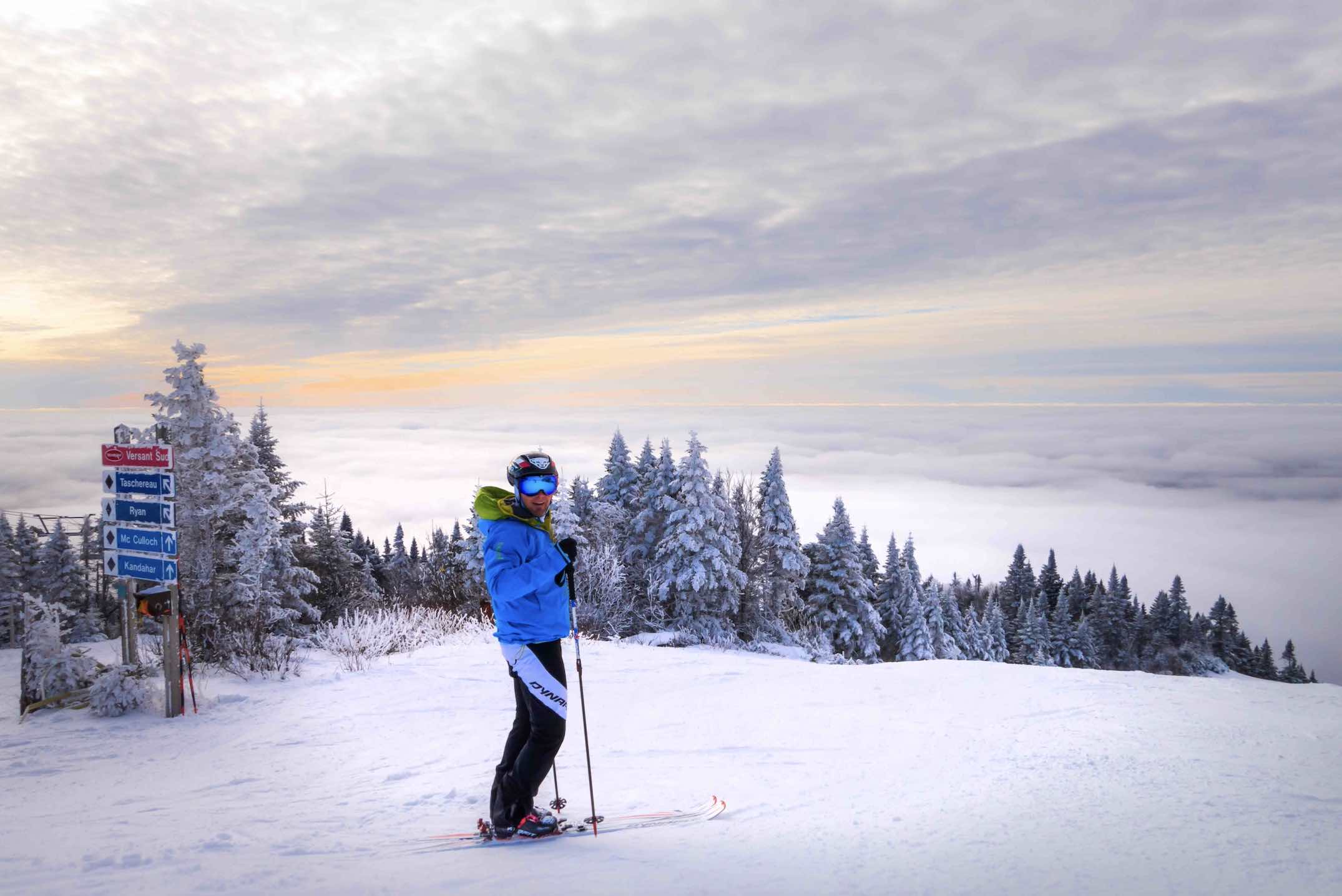 Tremblant winter things to do in Mont Tremblant with skiier at top of the mountains above clouds