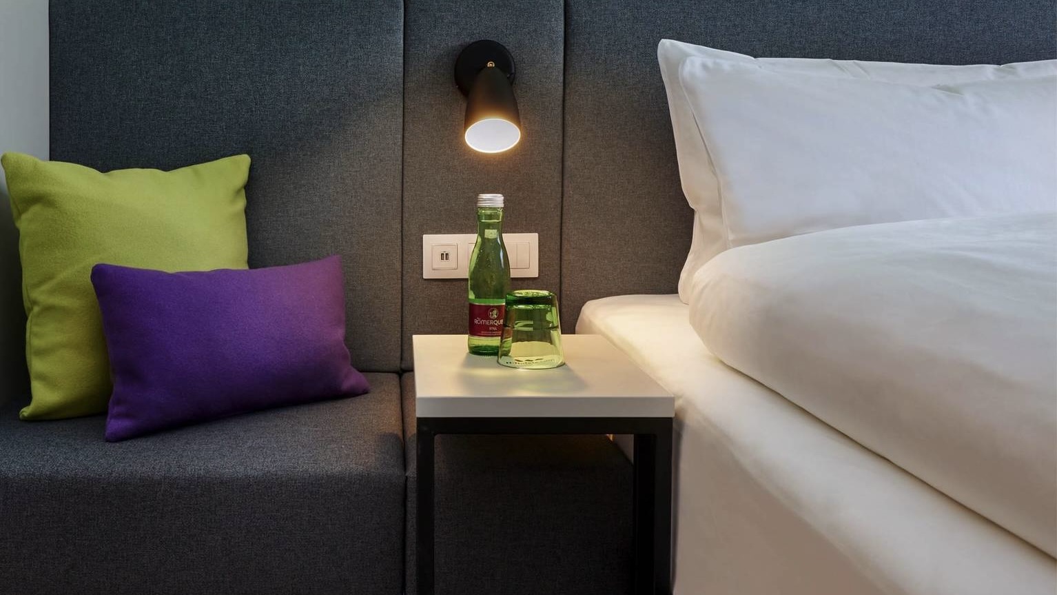 H+ Hotel Wien room with reading lamp and bottled water
